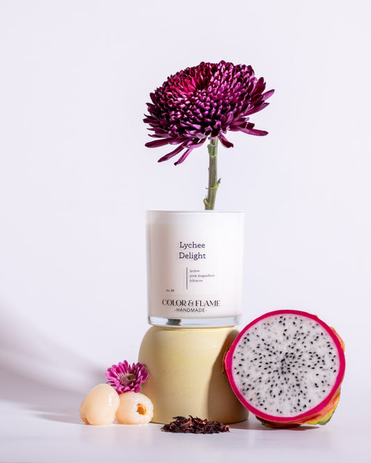 Color & Flame Handmade Lychee Delight candle styled with dragon fruit, lychees, purple flowers, and dried hibiscus.