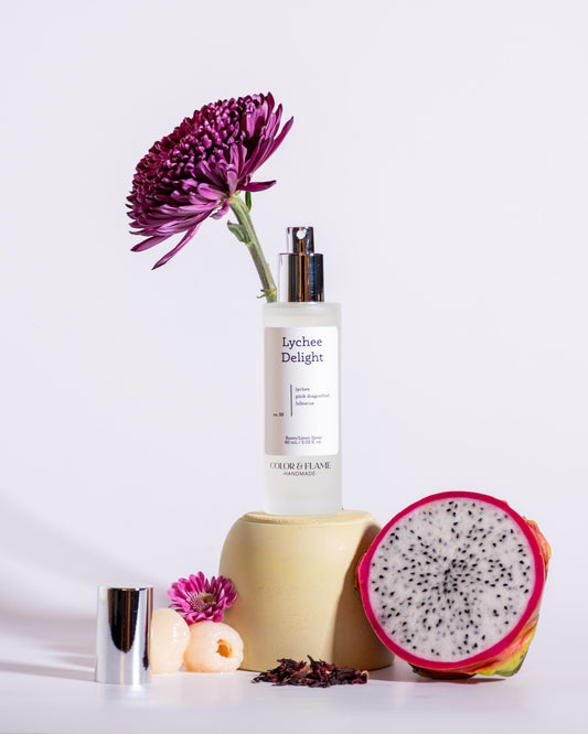 Color & Flame Handmade Lychee Delight room and linen spray styled with dragon fruit, lychees, pink flowers, and hibiscus.