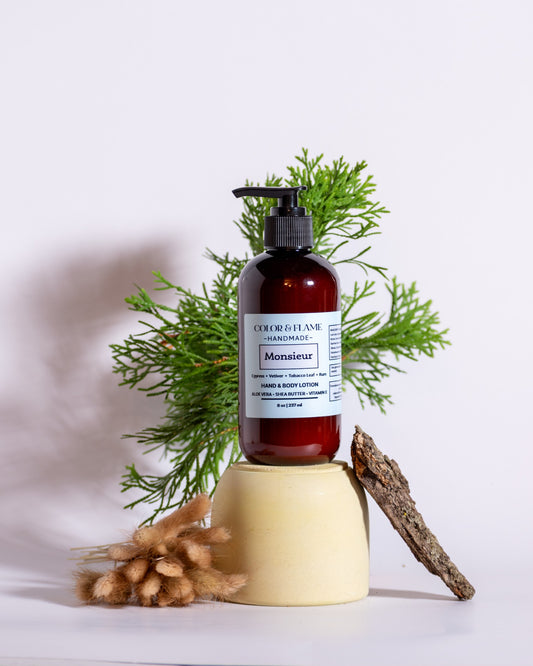 Color & Flame Handmade Monsieur hand and body lotion styled with evergreen branches, bark, and dried botanicals.
