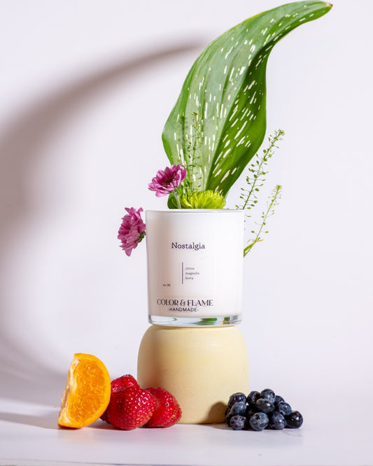 Color & Flame Handmade Nostalgia candle styled with orange, strawberries, blueberries, pink flowers, and a green leaf.