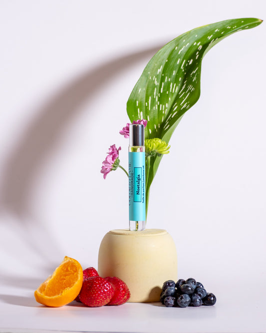 Color & Flame Handmade Nostalgia perfume oil styled with orange, strawberries, blueberries, green foliage, and pink flowers.