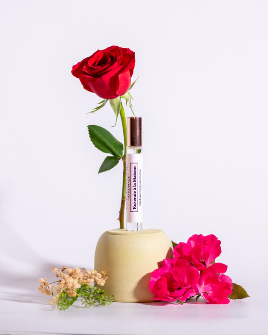 Color & Flame Handmade Roseraie à la Maison perfume oil styled with a red rose, bright pink roses, and delicate dried flowers.