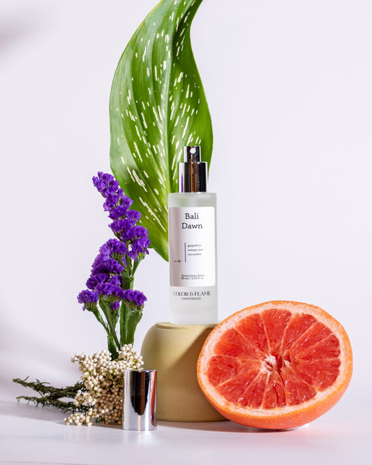 Color & Flame Handmade Bali Dawn room and linen spray styled with grapefruit, purple flowers, greenery, and white florals.
