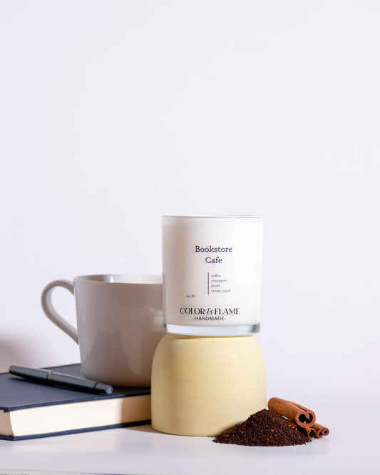 Color & Flame Handmade Bookstore Cafe candle styled with a coffee mug, book, ground coffee, and cinnamon sticks.
