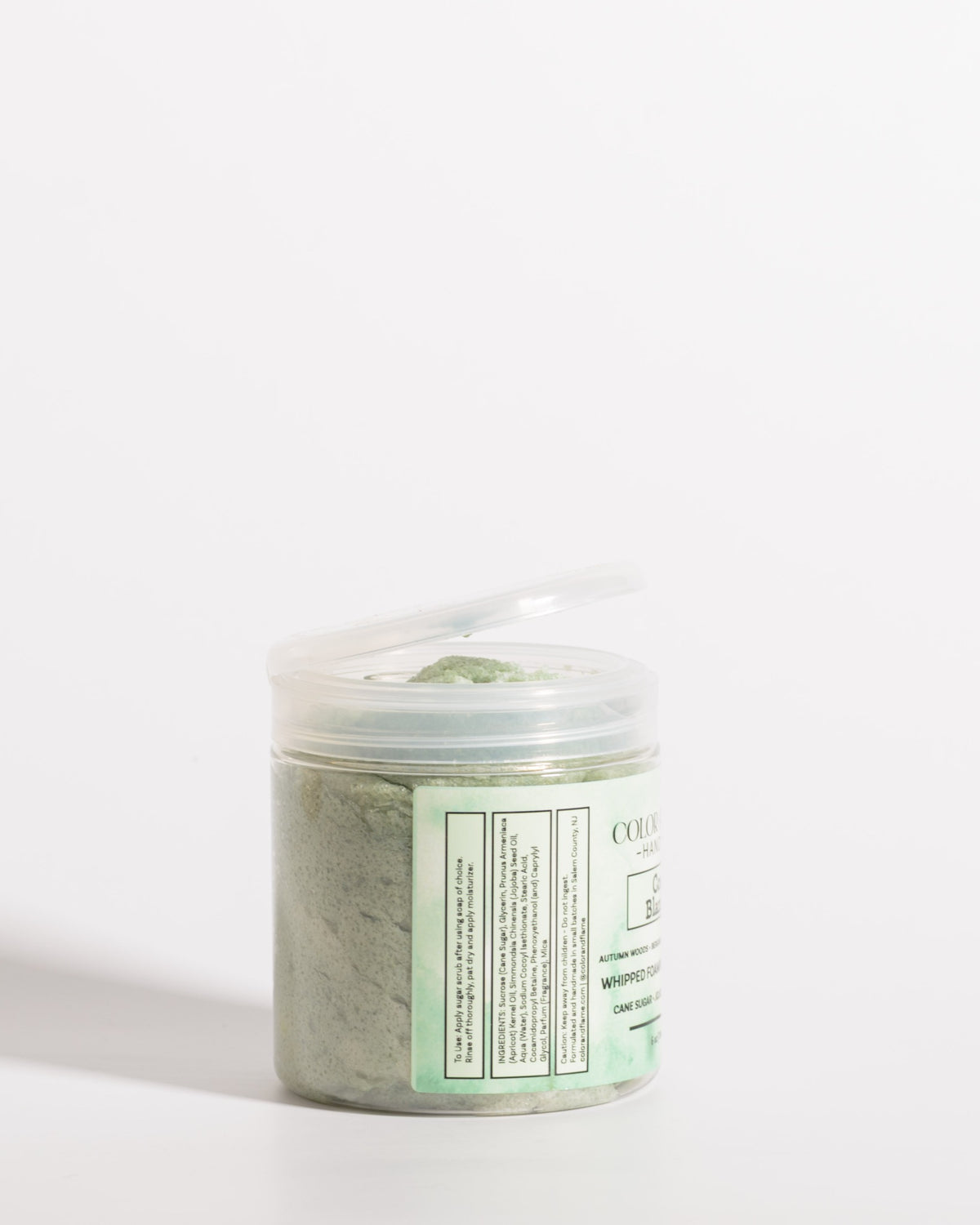 Color & Flame Handmade Cozy Blanket whipped foaming sugar scrub in an open clear jar showing the green scrub.
