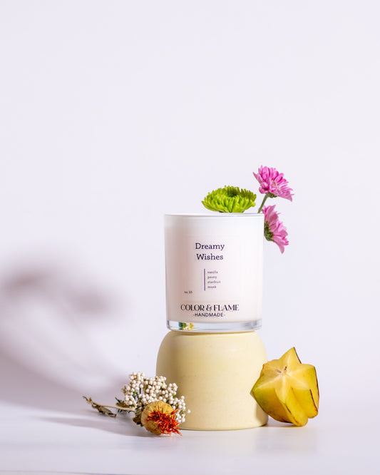 Color & Flame Handmade Dreamy Wishes candle styled with starfruit and pink, green, and white flowers.
