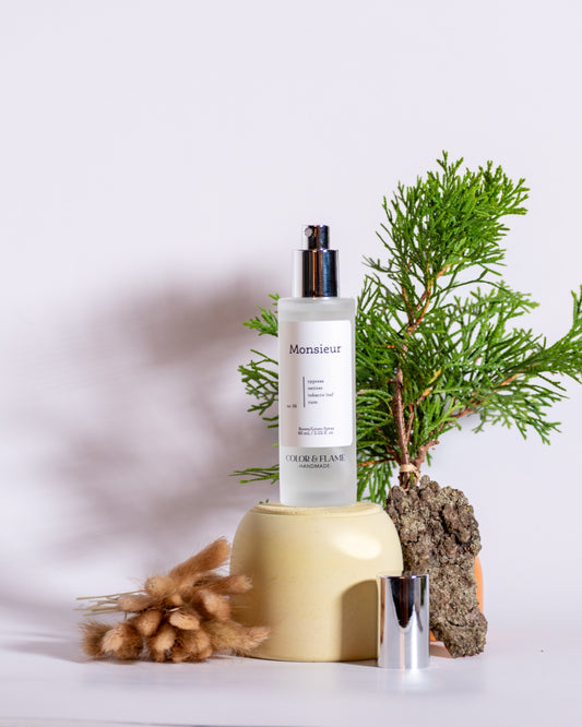 Color & Flame Handmade Monsieur room and linen spray styled with evergreen branches, bark, and soft dried florals.
