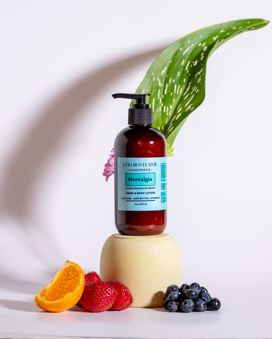 Color & Flame Handmade Nostalgia hand and body lotion styled with orange, strawberries, blueberries, and green foliage.
