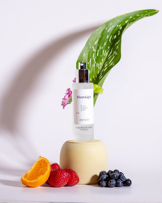 Color & Flame Handmade Nostalgia room and linen spray styled with orange, strawberries, blueberries, flowers, and greenery.
