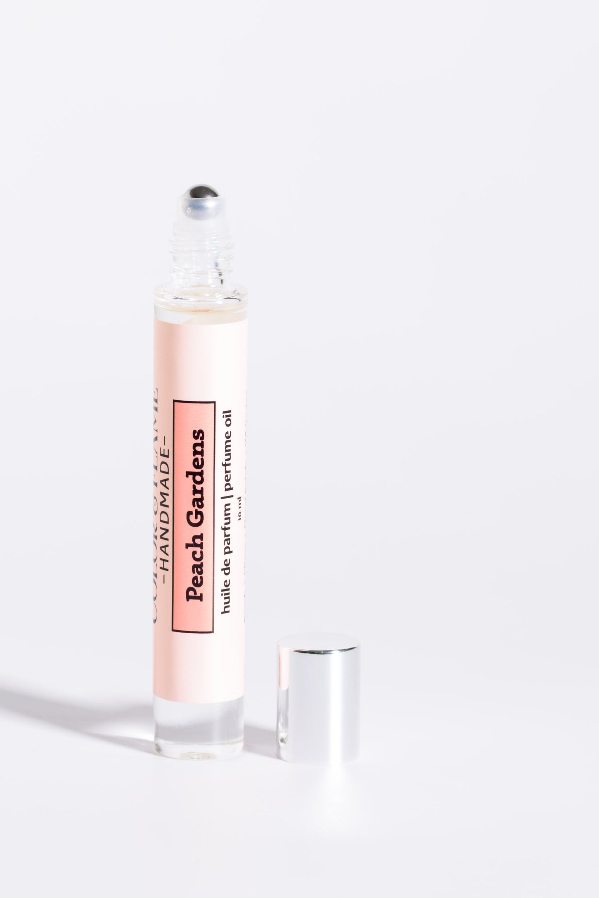 Color & Flame Handmade Peach Gardens 10 ml perfume oil with cap removed to show the rollerball.

