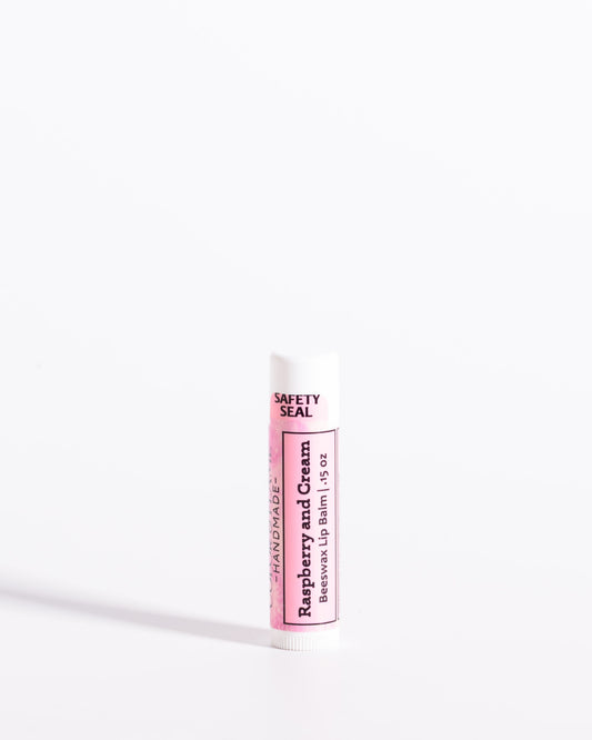Color & Flame Handmade Raspberry and Cream beeswax lip balm in a white tube with a pink label.