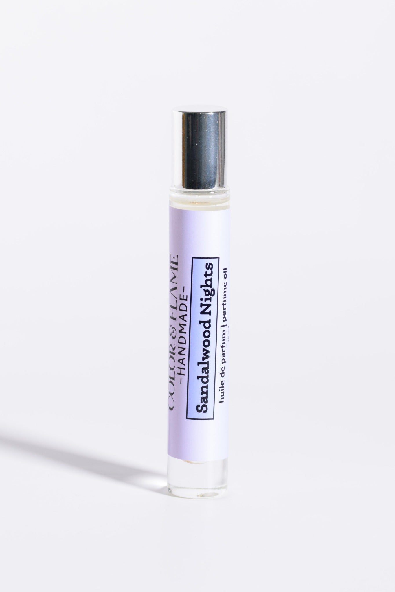 Color & Flame Handmade Sandalwood Nights 10 ml roll-on perfume oil with its silver cap attached.
